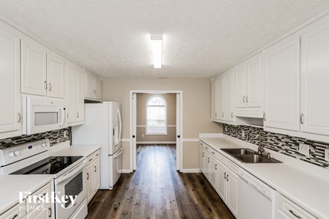 an empty kitchen with white cabinets and white appliances