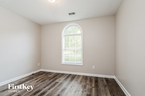 the second bedroom with hardwood flooring and an arched window