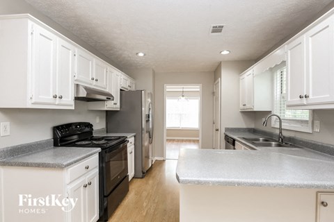 a kitchen with white cabinets and a black stove and refrigerator
