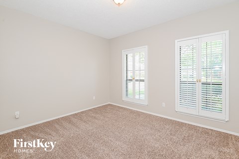 a bedroom with carpet and two windows