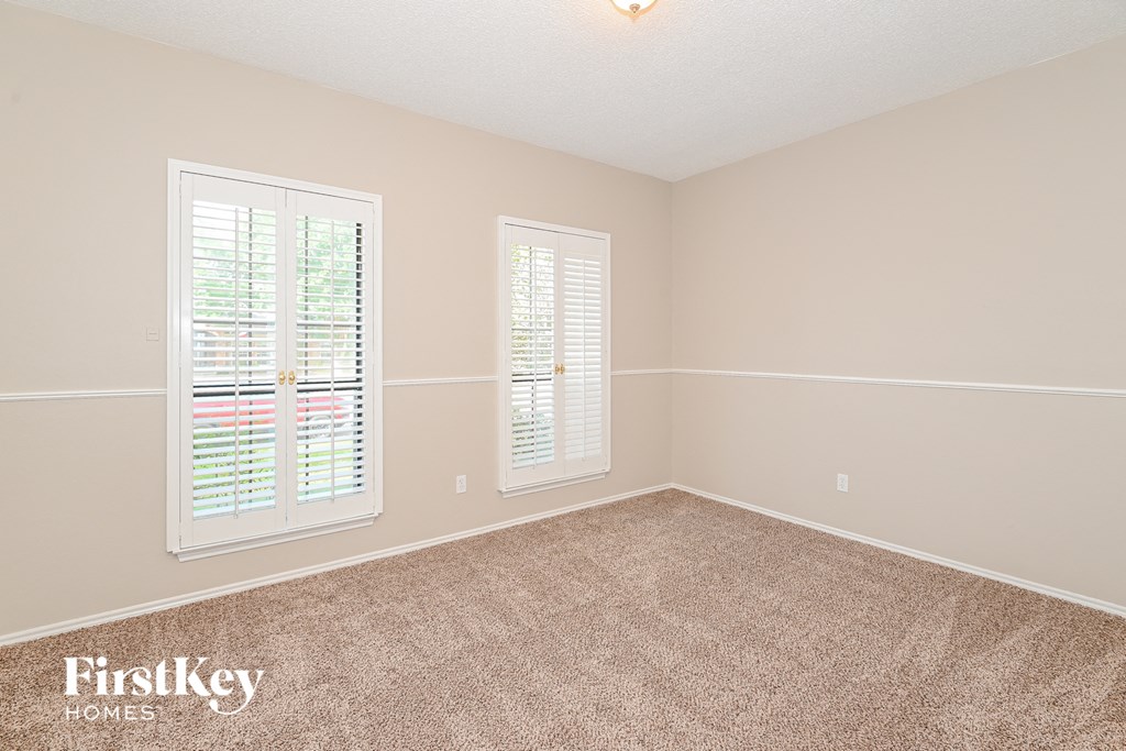 a bedroom with a carpeted floor and two windows