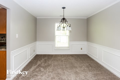 an empty dining room with white wainscoting and a window