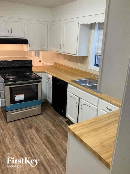 A kitchen with a stove top oven and white cabinets.