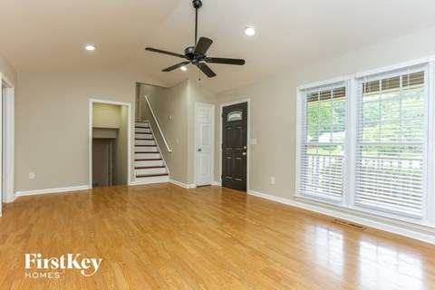 A spacious room with a ceiling fan and wooden flooring.