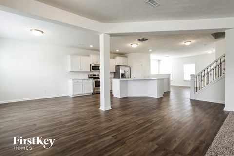 a renovated living room and kitchen with white walls and wood floors
