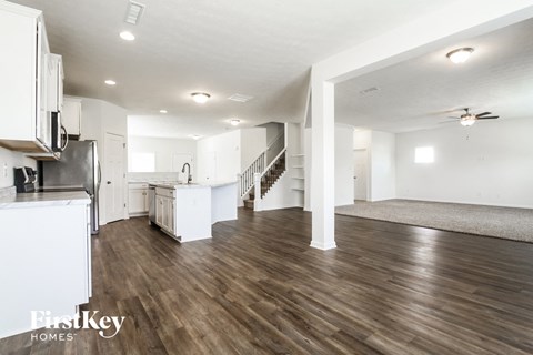 a renovated living room and kitchen with white walls and wood flooring