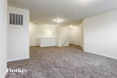 a spacious living room with carpet and white walls