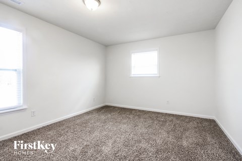 a bedroom with white walls and carpet and a window