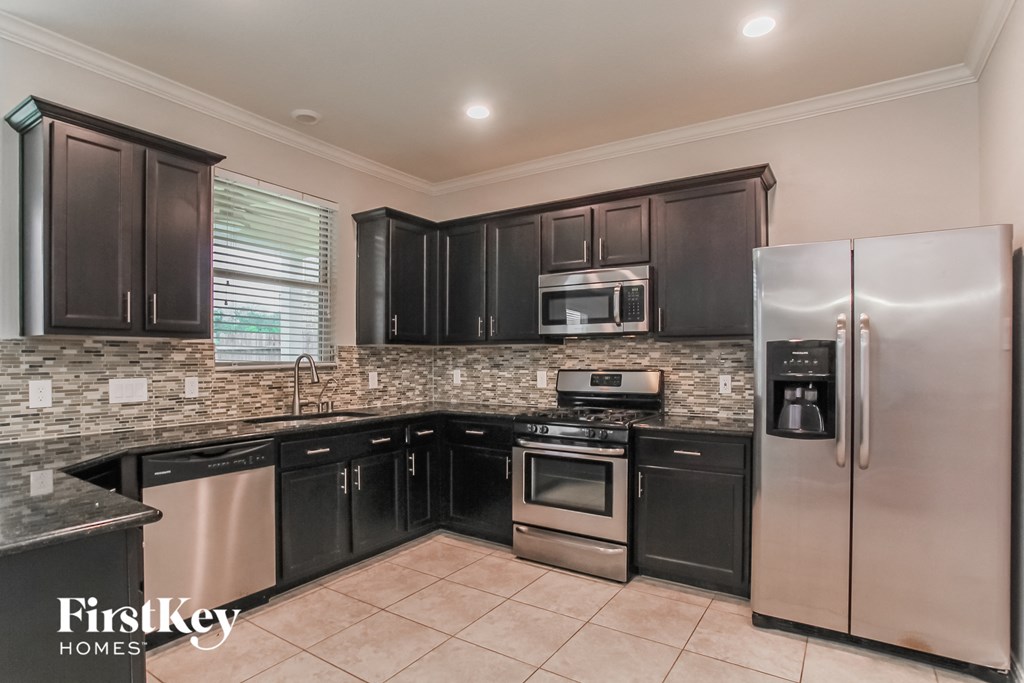 a kitchen with black cabinets and stainless steel appliances