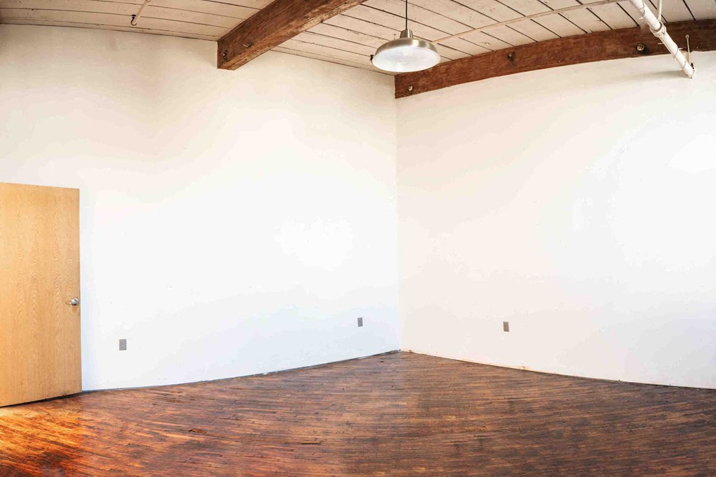 an empty room with wood floors and a white wall