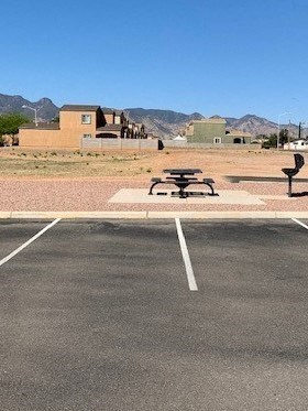 A parking lot with a picnic table and benches in the middle.