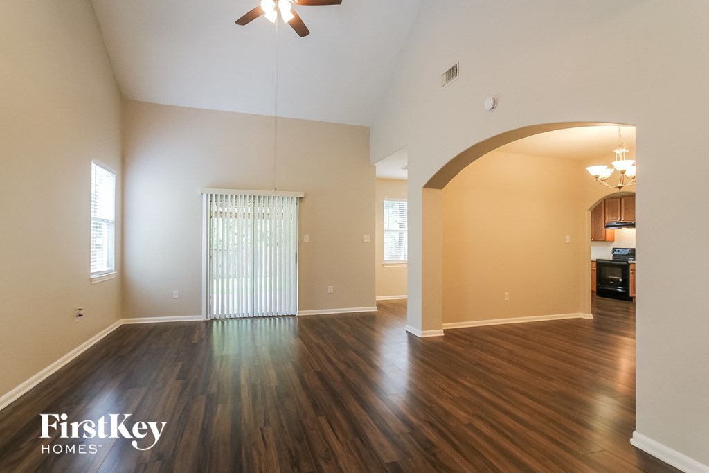 an empty living room with wood flooring and a ceiling fan