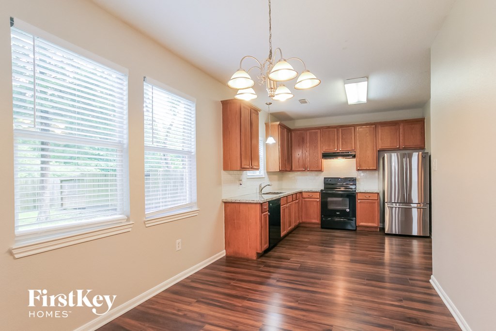 an empty kitchen with wood flooring and a large window
