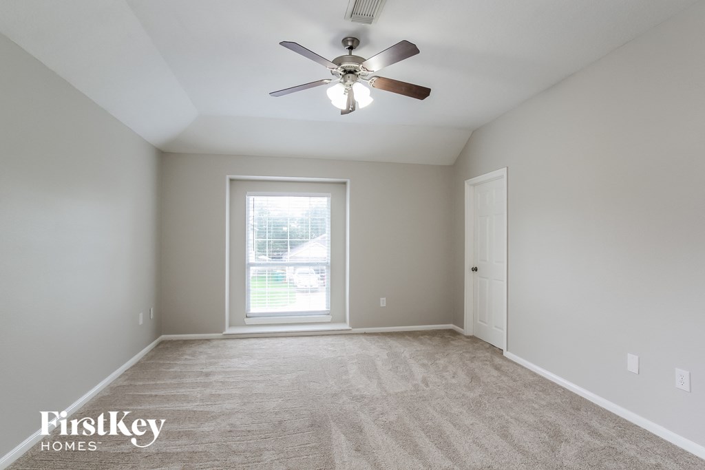 an empty room with a ceiling fan and a window