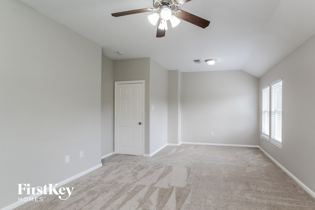 a clean and empty bedroom with a ceiling fan and window