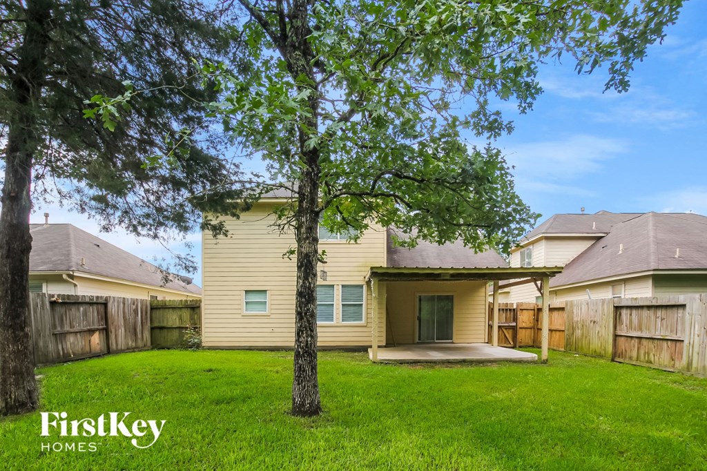 a backyard with a yellow house and a tree