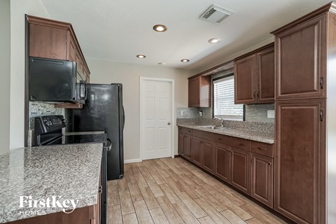 A kitchen with brown cabinets and a granite countertop.