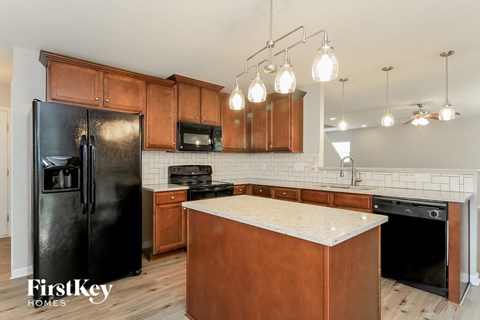 A kitchen with wooden cabinets and a black refrigerator.