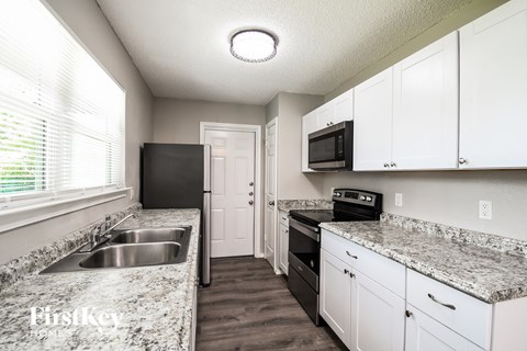 A kitchen with granite countertops and white cabinets.
