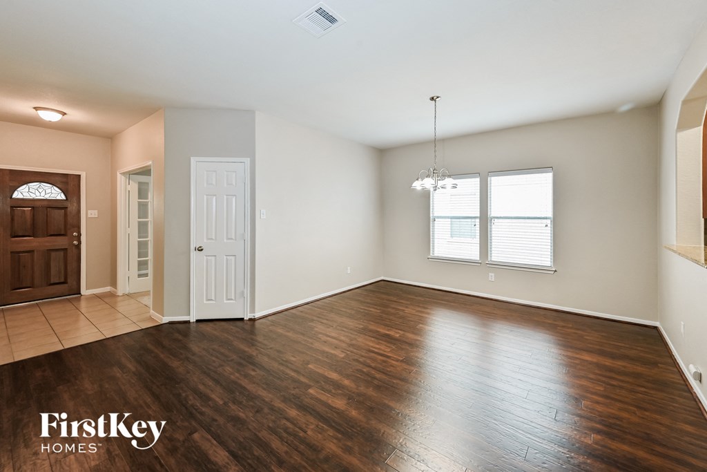 A spacious room with wooden flooring and a chandelier hanging from the ceiling.