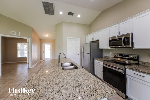 a kitchen with white cabinets and granite counter tops and black appliances