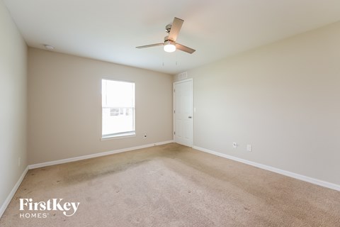 a spacious living room with carpet and a ceiling fan