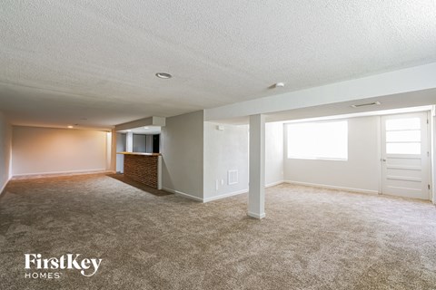 a living room with carpet and a door to a kitchen