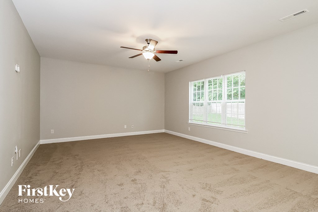 the master bedroom has a large window and a ceiling fan