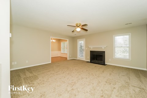 A spacious living room with a fireplace and a ceiling fan.