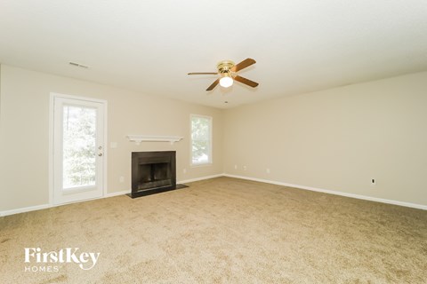 A spacious room with a fireplace and a ceiling fan.