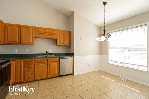 a kitchen with wooden cabinets and tiled floors and a large window