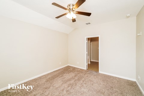 a spacious living room with carpet and a ceiling fan