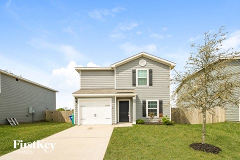 a gray house with a white garage door and a lawn