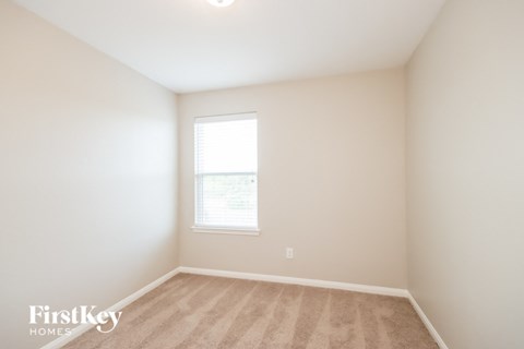 a bedroom with white walls and a window