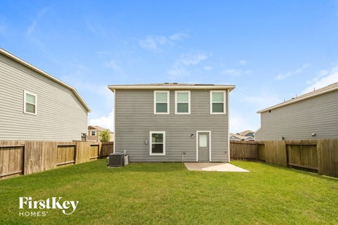 a backyard with a gray house and a grassy yard