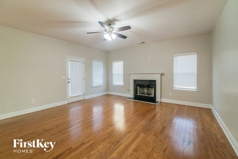 an empty living room with a fireplace and a ceiling fan