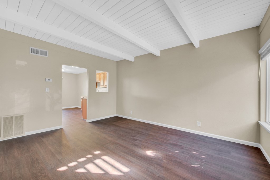 the living room and dining room of an empty house with wood flooring