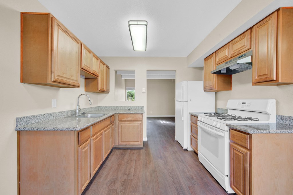 an empty kitchen with wooden cabinets and white appliances