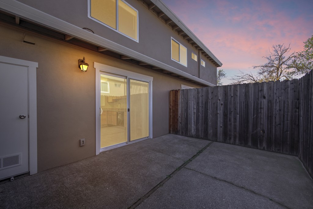 a patio in front of a house with a wooden fence