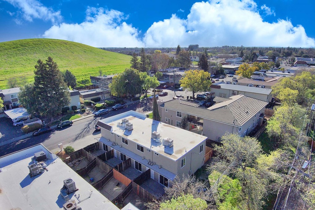 an aerial view of a building with a green hill in the background