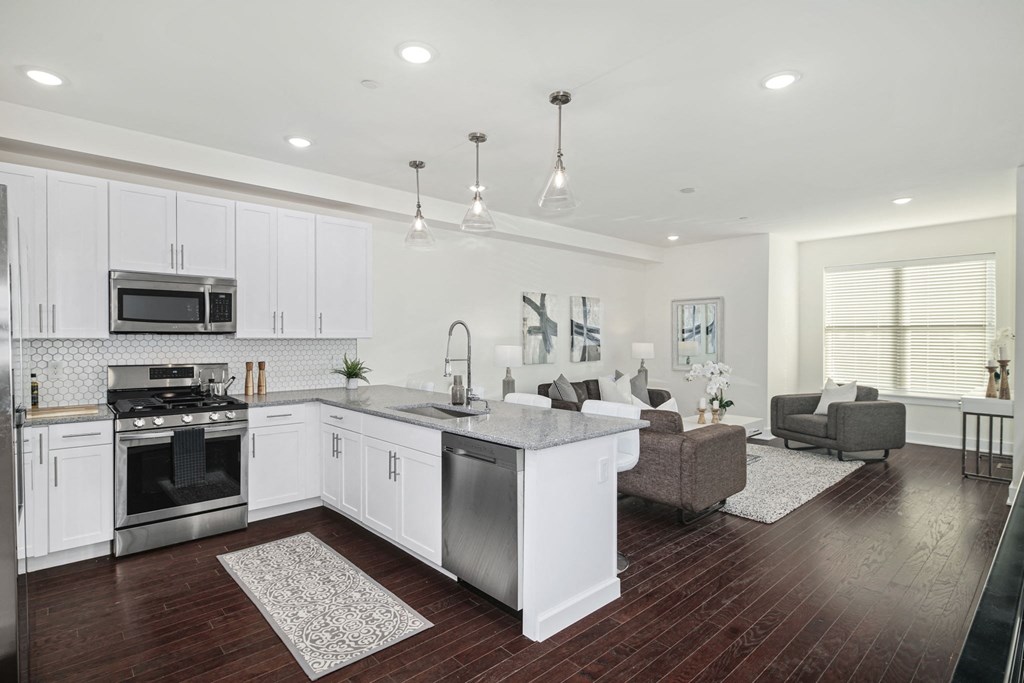 a white kitchen with a large island and a living room