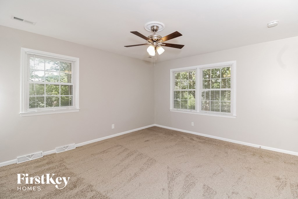 a bedroom with carpet and a ceiling fan and two windows