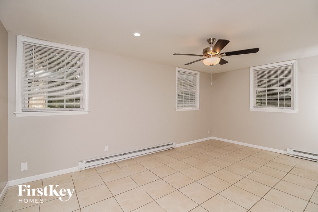 an empty living room with a ceiling fan and a tiled floor