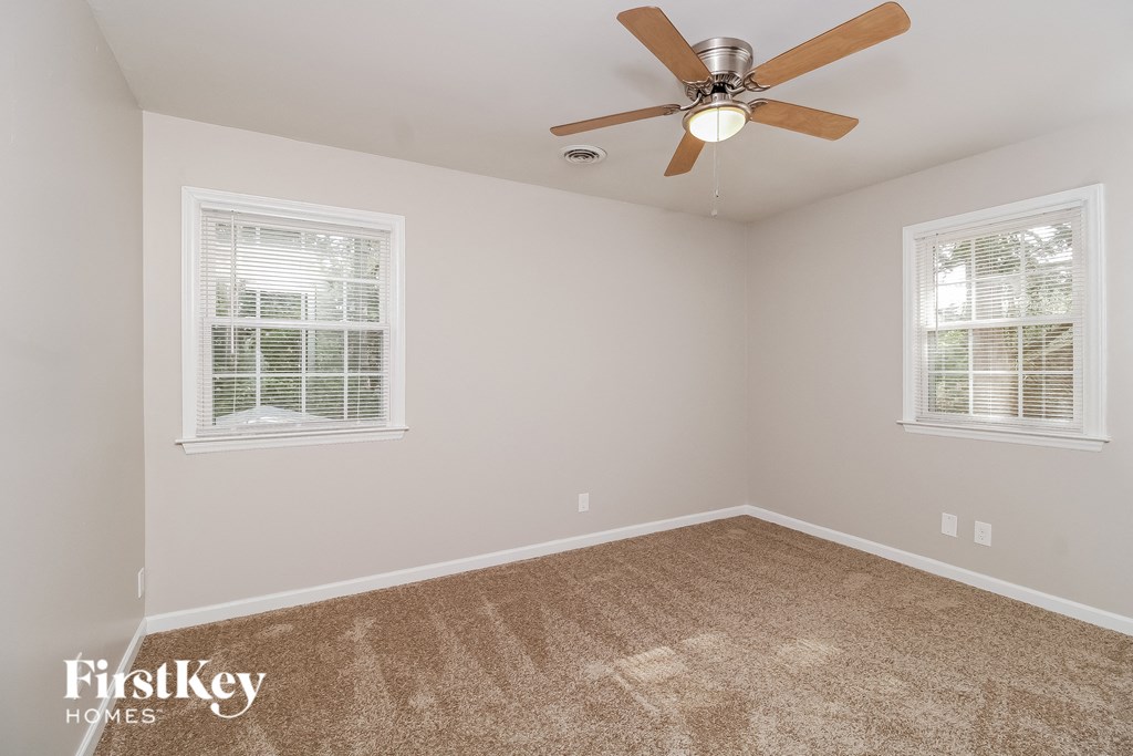 a bedroom with carpet and a ceiling fan and two windows