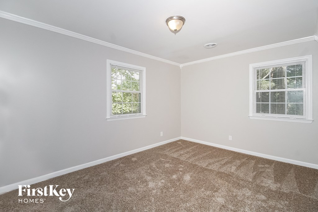 a empty room with carpet and two windows