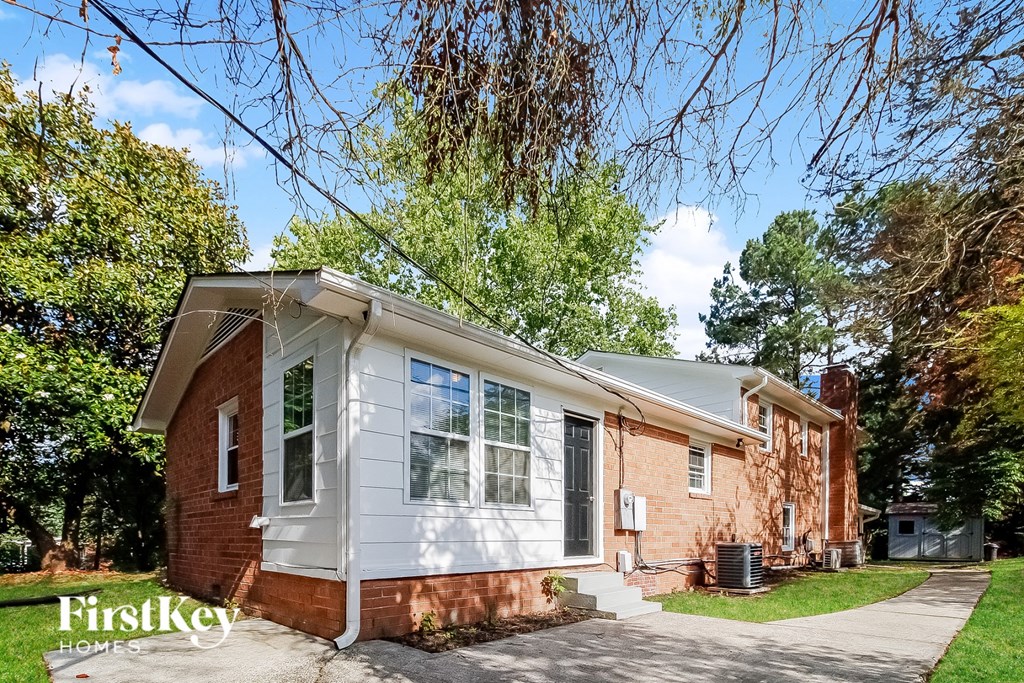a small brick house with white siding and a sidewalk