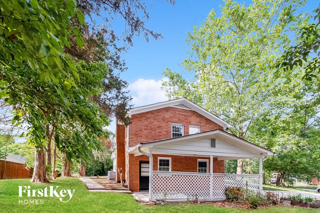 a small brick house with a white porch and trees