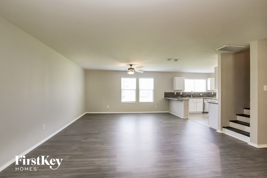 A spacious empty room with a kitchen in the background.