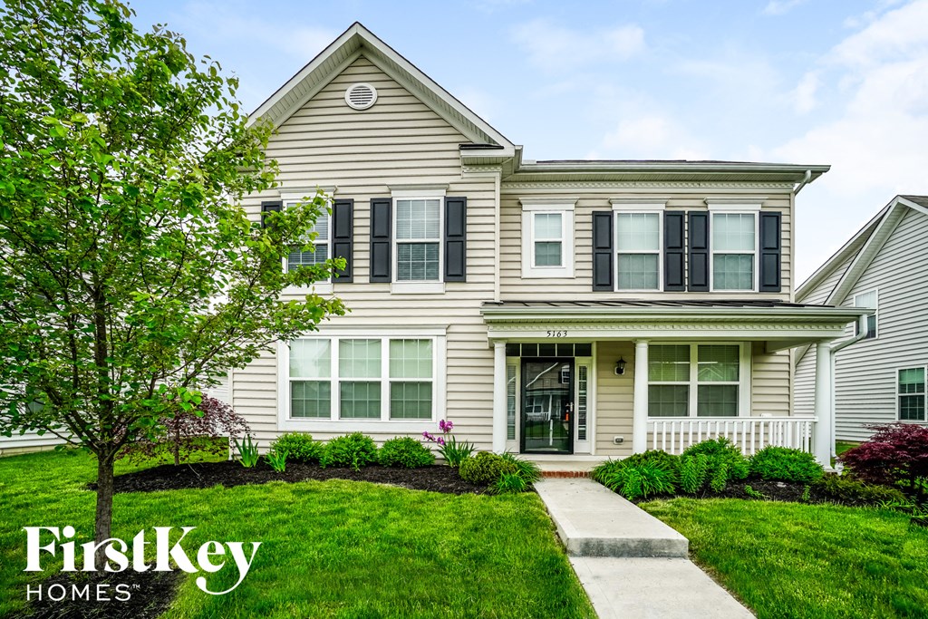 a white house with black shutters and a green lawn