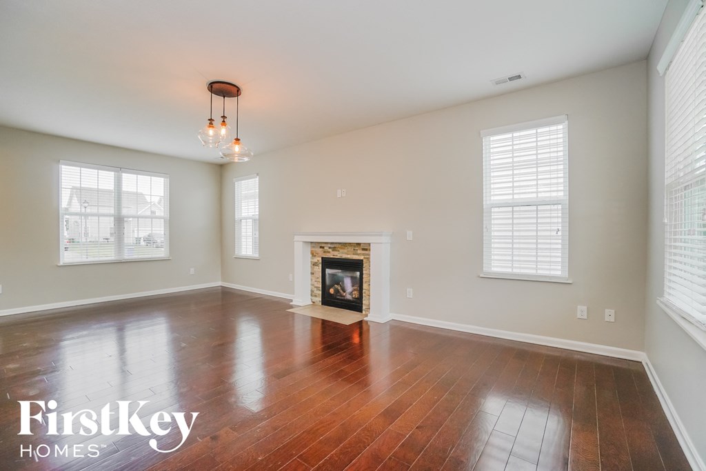 an empty living room with a fireplace and wooden floors